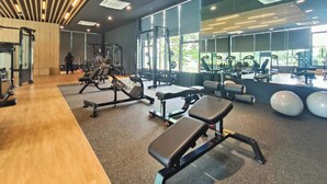 A modern gym with various exercise equipment, large windows, and a wooden ceiling design. - MayaBay Residences Bandar Gamuda Cove (Banting)