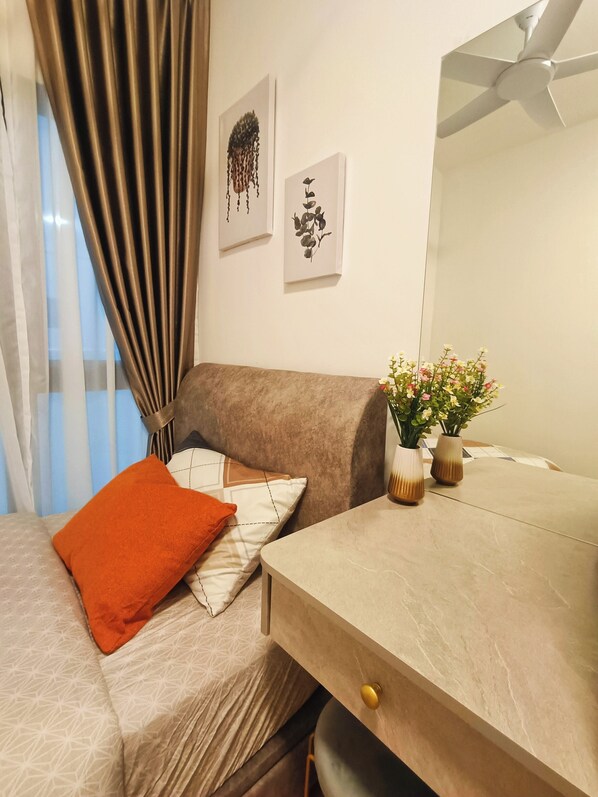 Une pièce avec un canapé, une petite table ornée de vases et un ventilateur de plafond.