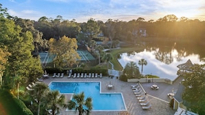 Ein Resort mit Swimmingpool, Liegestühlen, Tennisplatz und Seeblick.