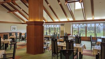 A spacious dining area with high ceilings, large windows, and a view of the outdoors.