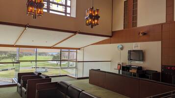 En rymlig lobby med utsikt över en golfbana, bekväma lädersitsar, en receptionsdisk och modern belysning.
