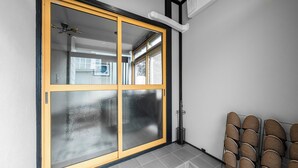 Une pièce dotée d’une grande porte-fenêtre coulissante, d’un sol carrelé et d’un coin salon avec des fauteuils.
