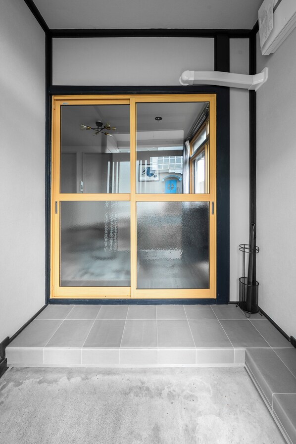 A room with a sliding glass door leading to a balcony, a ceiling fan, and a tiled floor. - AKATSUKI (Kamifurano)