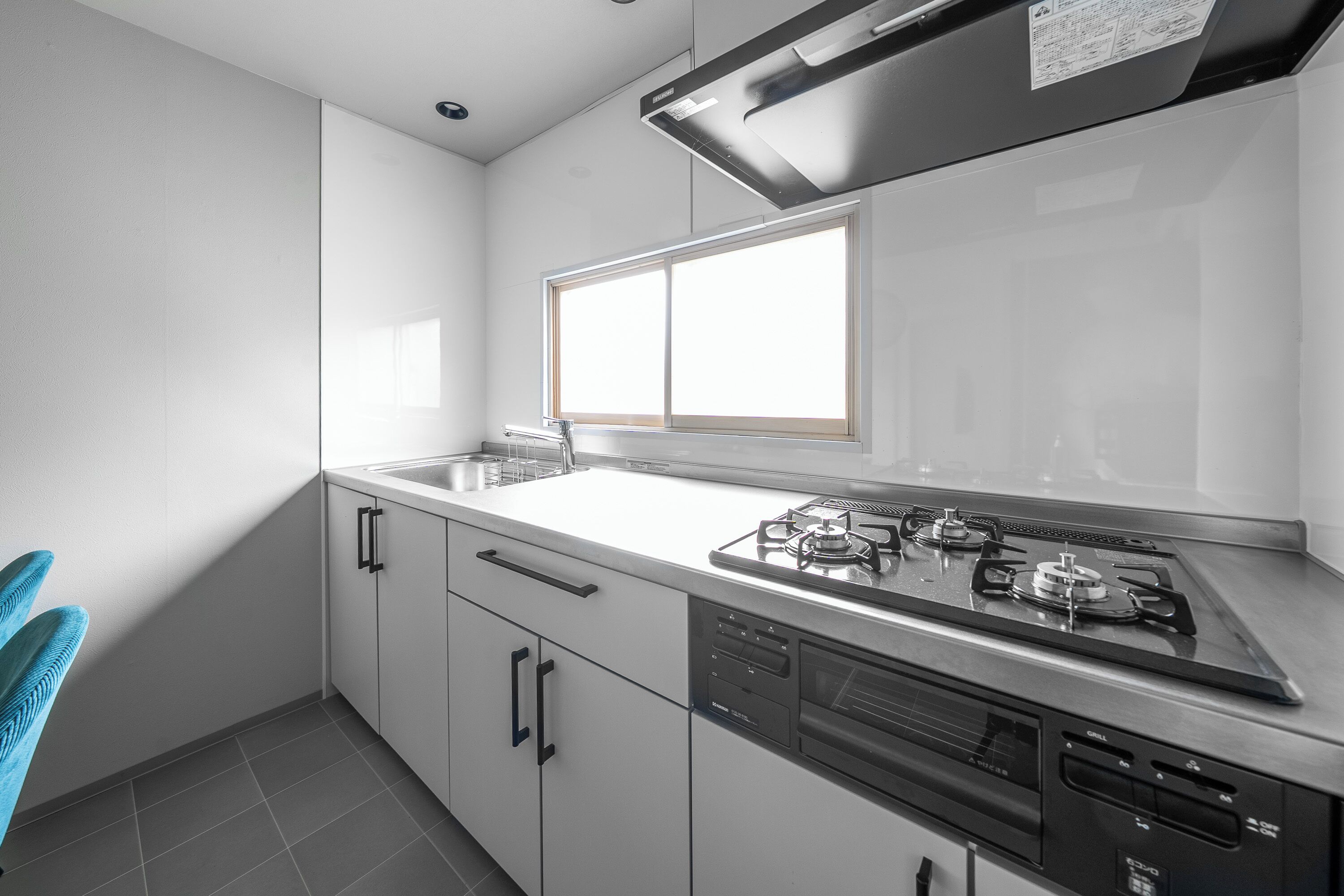 A modern kitchen with white cabinets, a stainless steel stove, and a window above the sink.