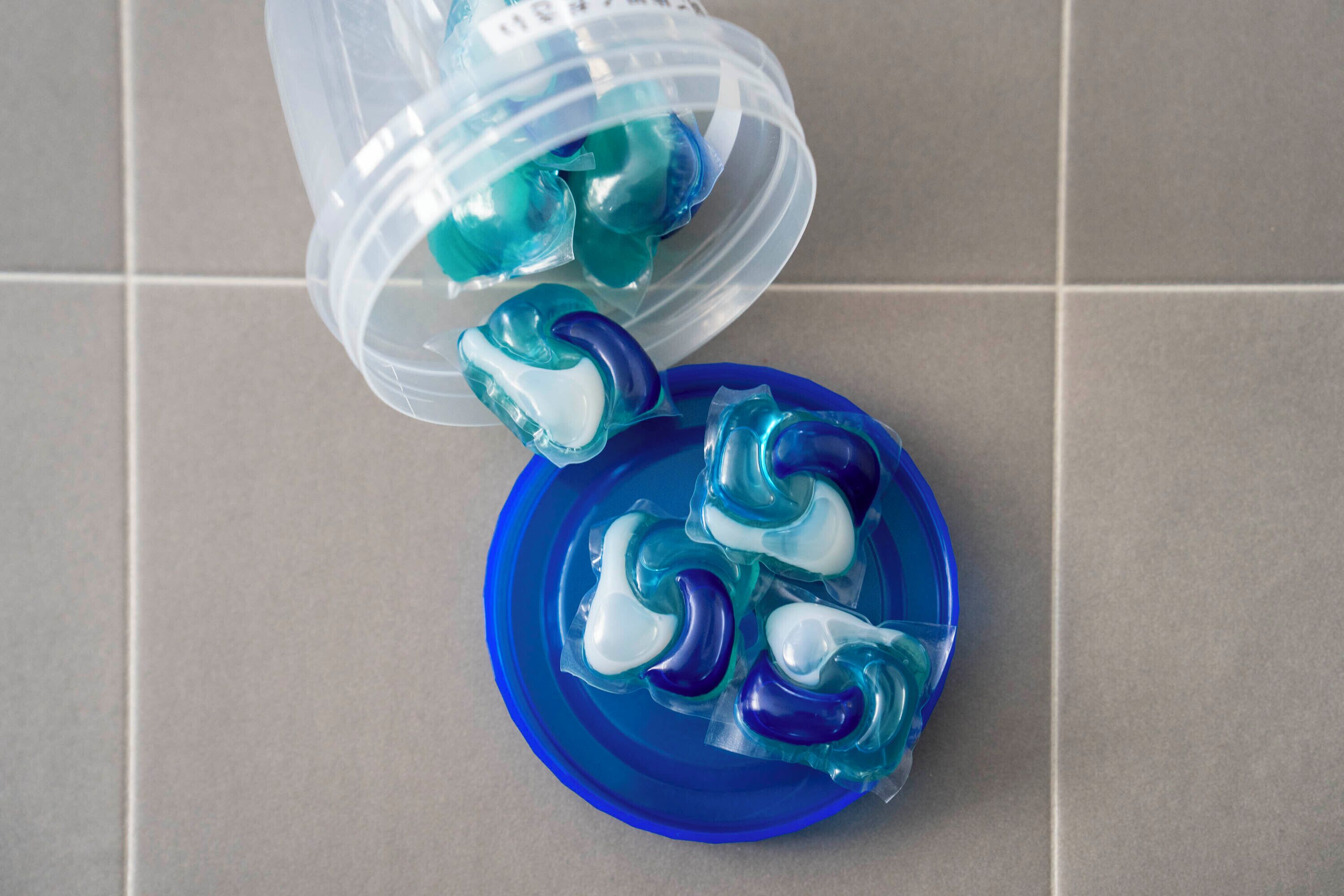 A plastic container tipped over with blue and white gel-like objects spilling onto a blue surface.