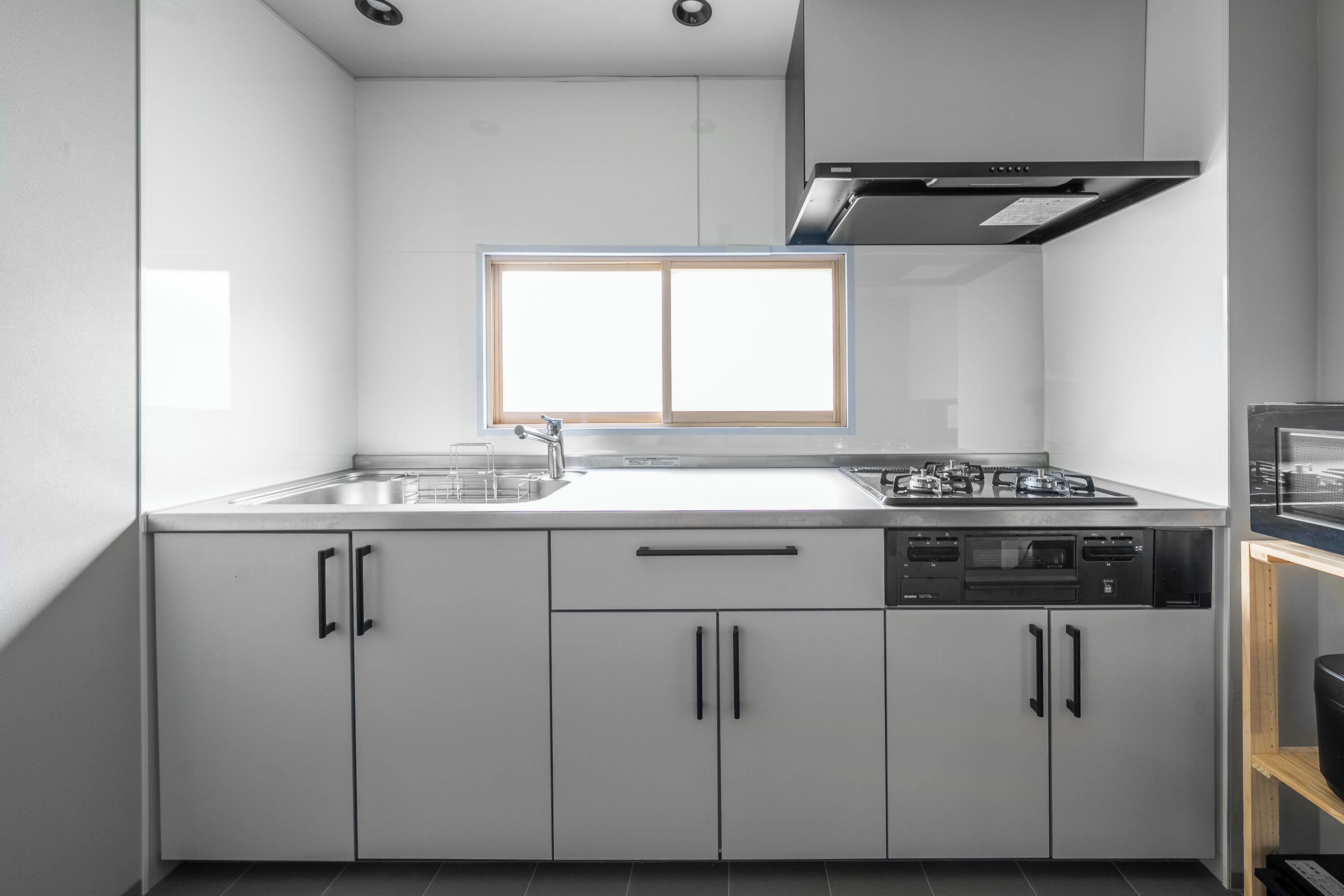 A modern kitchen with white cabinets, a built-in oven, and a window above the sink.