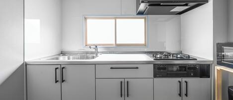 A modern kitchen with white cabinets, a built-in oven, and a window above the sink.