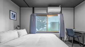 Une chambre d’hôtel moderne, dotée d’un grand lit, d’un bureau et d’une fenêtre avec des rideaux.