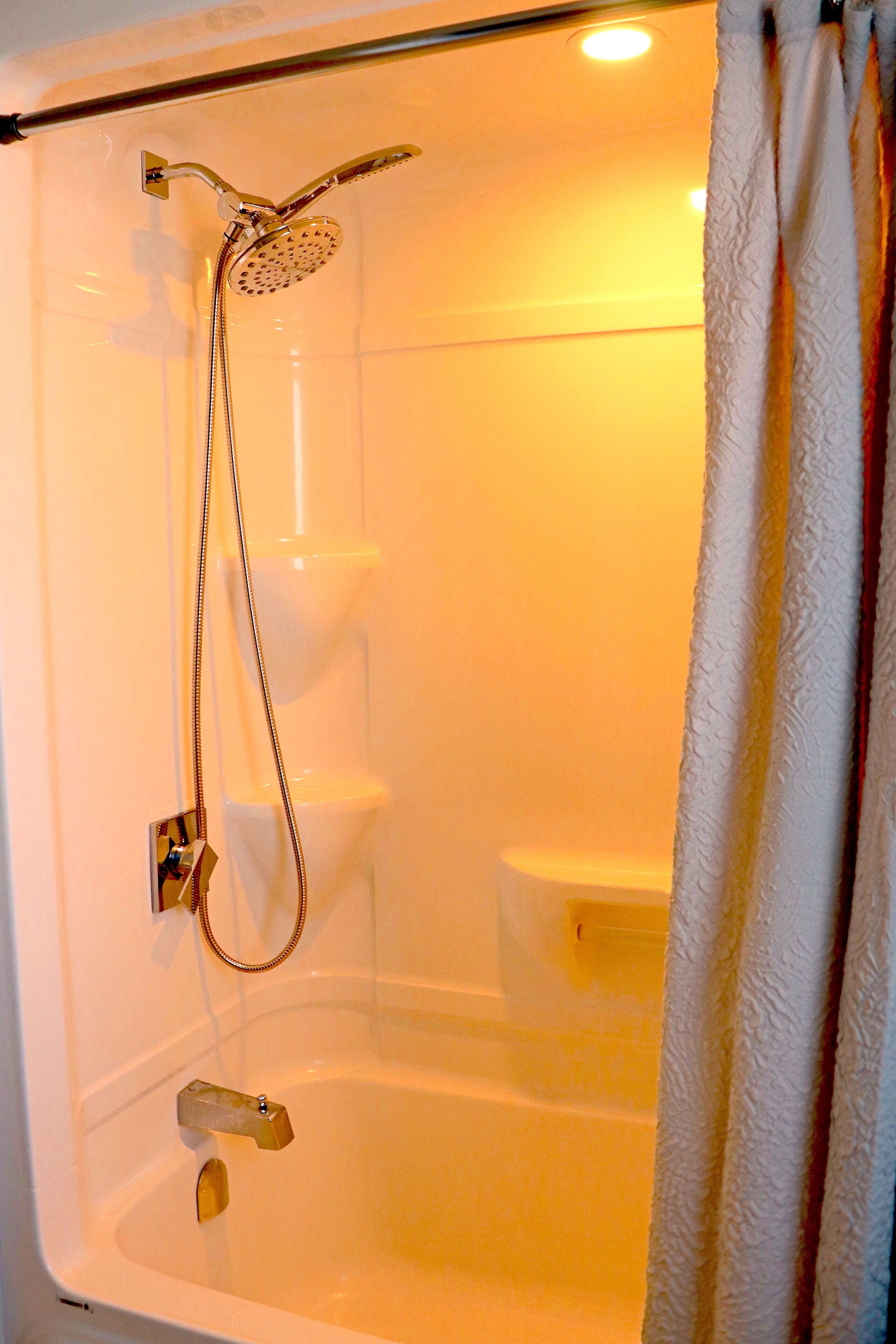 Une douche équipée d’un pommeau de douche à main et d’un robinet fixé au mur.