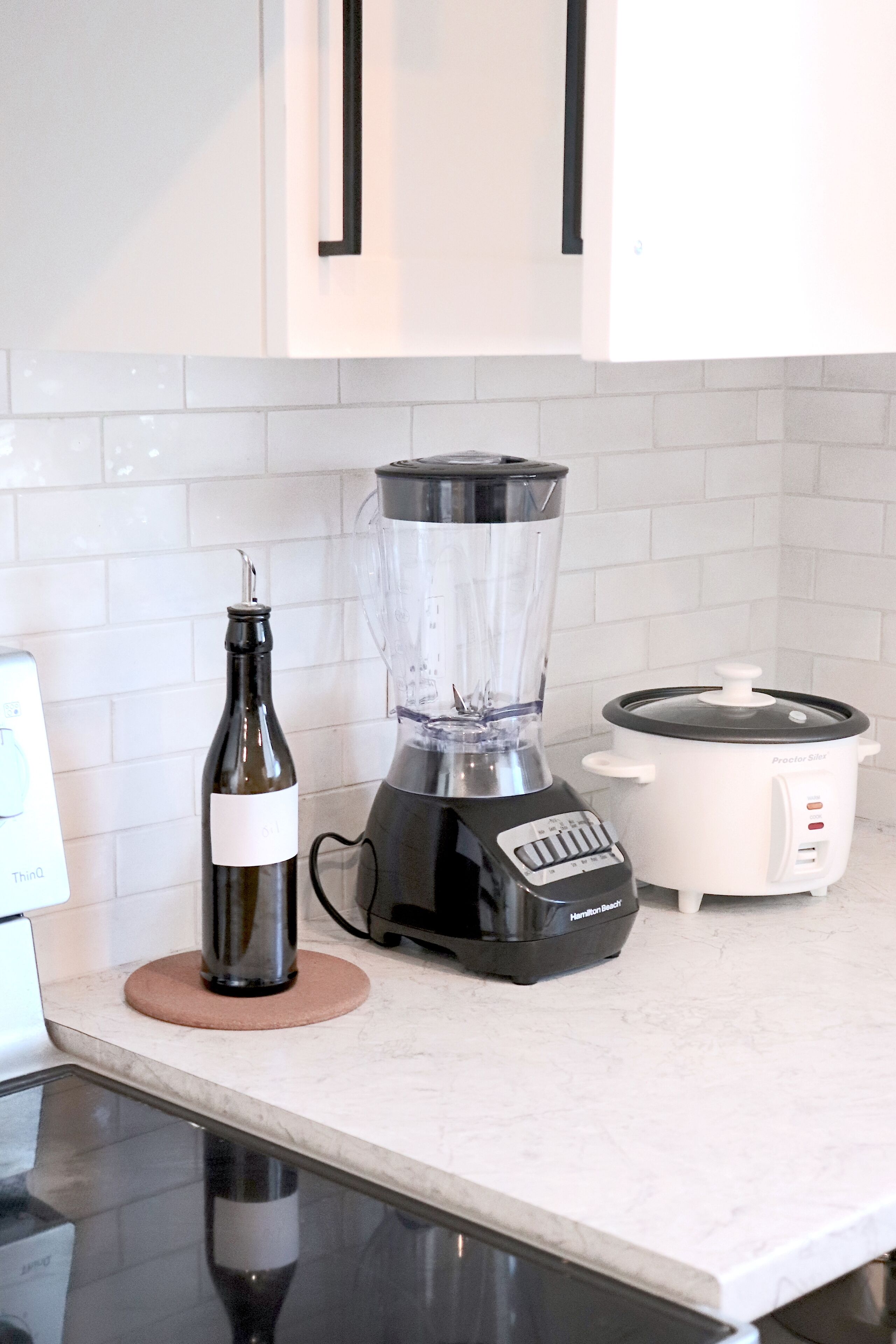 Eine Küche mit Arbeitsplatte, einem Mixer, einem Slow-Cooker und einer Weinflasche.