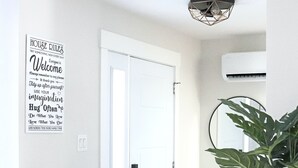 Un pasillo con una puerta blanca, un cartel en la pared con citas motivacionales y una planta en maceta.