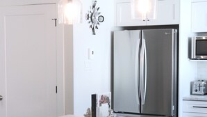 Una cocina moderna con una isla central, electrodomésticos de acero inoxidable e iluminación colgante.