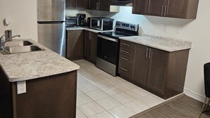 A modern kitchen with dark wooden cabinets, stainless steel appliances, and a granite countertop. - Cozy clean, family sized house. (Cambridge)