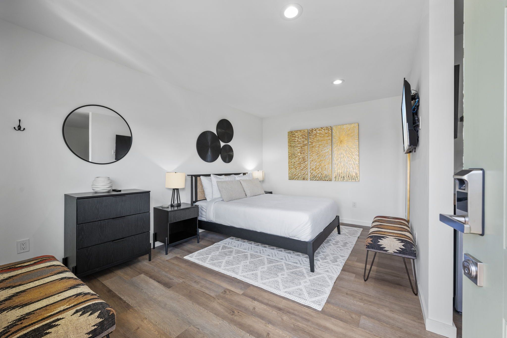 Une chambre à coucher moderne, avec un lit, une commode, des tables de chevet et un téléviseur.