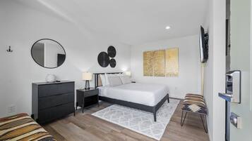 A modern bedroom with a bed, dresser, nightstands, and a TV.
