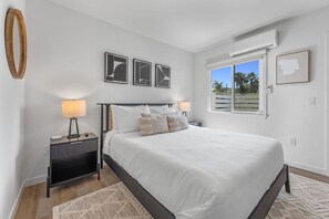 Un dormitorio con cama, mesitas de noche, decoración en la pared y ventana con vistas.