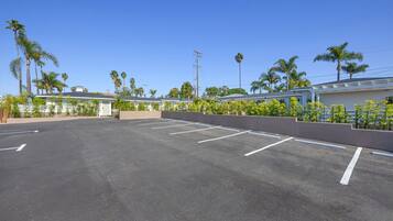 A parking lot with marked spaces, surrounded by buildings and palm trees.