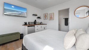 Un dormitorio moderno con una cama grande, un escritorio empotrado y vistas a la playa.