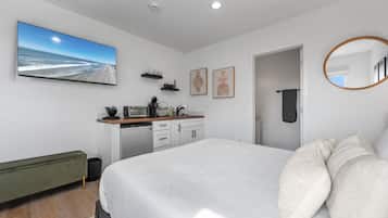 Une chambre moderne avec un grand lit, un bureau intégré et une vue sur la plage.
