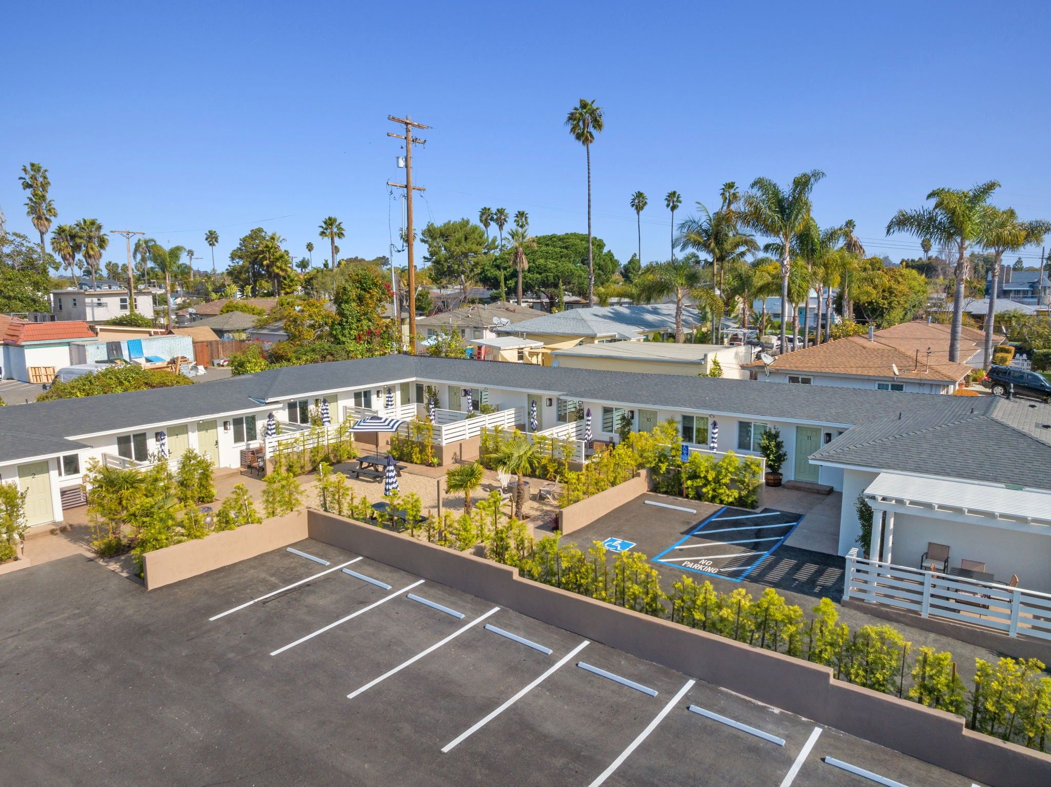 Un motel comprenant plusieurs chambres, un parking et un petit jardin.