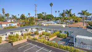 Un motel con varias habitaciones, un estacionamiento y un pequeño jardín.