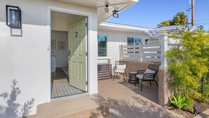 Una propiedad residencial con puerta verde, un patio con mobiliario exterior y cerca blanca.