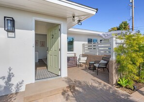 A residential property with a green door, a patio with outdoor furniture, and a white fence.