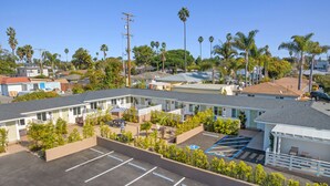 Un motel con varias habitaciones, un estacionamiento y una pequeña zona de piscina.