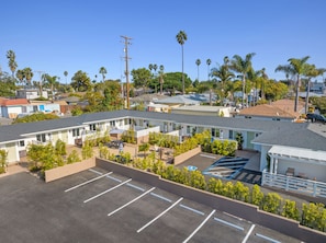 Un motel con varias habitaciones, un estacionamiento y una pequeña zona de piscina.