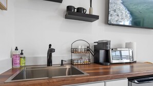 Una cocina moderna con electrodomésticos de acero inoxidable, cafetera y lavamanos.
