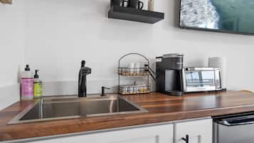 A modern kitchen with stainless steel appliances, a coffee maker, and a sink.