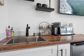 Una cocina moderna con electrodomésticos de acero inoxidable, cafetera y lavamanos.