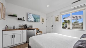 Een slaapkamer met een bed, een bureau, een magnetron en een televisie.