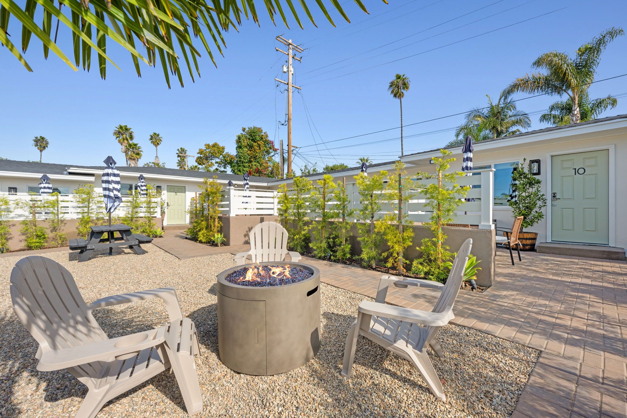 A patio area with Adirondack chairs, a fire pit, and a small building with a door labeled '10'.