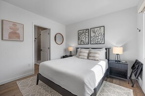 A bedroom with a bed, bedside tables, a mirror, and artwork on the walls.