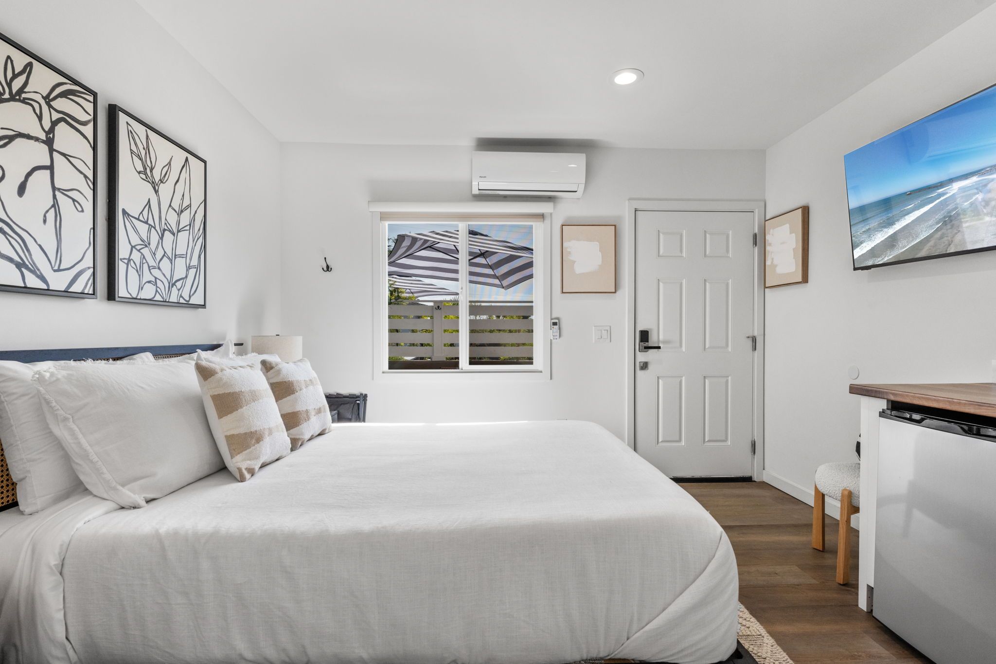 Quarto com cama, escrivaninha e vista para o exterior.
