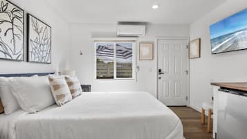 Quarto com cama, escrivaninha e vista para o exterior.