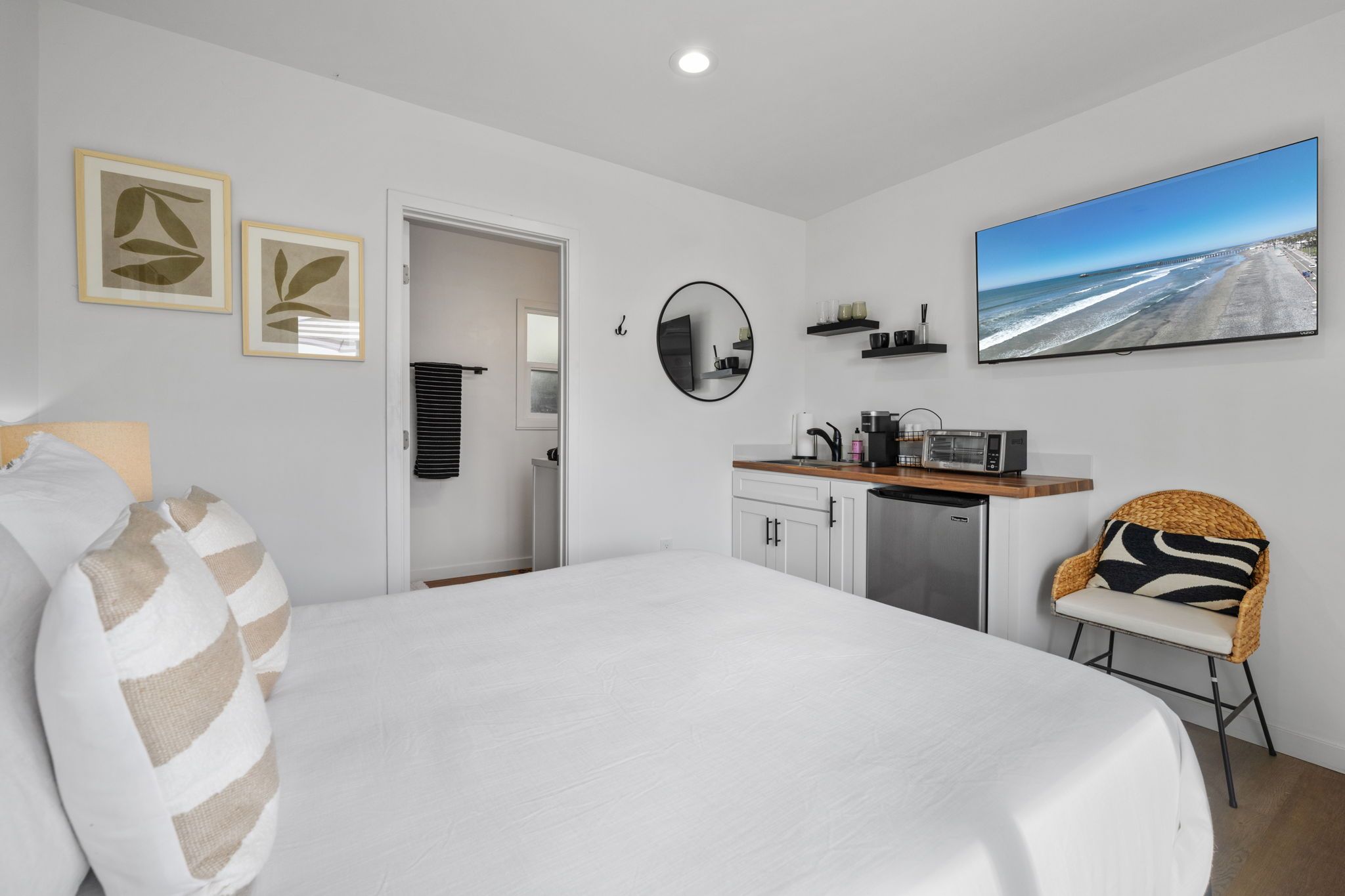 Une chambre moderne dotée d’un grand lit, d’une kitchenette, d’un coin repas et offrant une vue sur la plage.