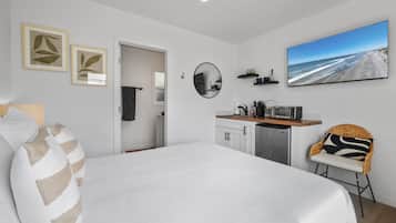 Une chambre moderne dotée d’un grand lit, d’une kitchenette, d’un coin repas et offrant une vue sur la plage.
