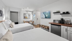 Ein modernes Hotelzimmer mit zwei Betten, einer Essecke und einer Küchenzeile.