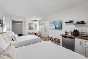 Une chambre d’hôtel avec deux lits, une kitchenette, un coin repas et une salle de bain.