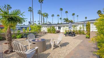 An outdoor patio with Adirondack chairs, a fire pit, and a pool table.
