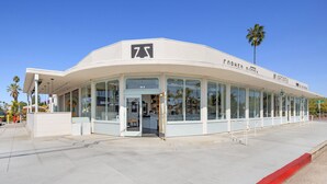 Un bâtiment moderne à la façade incurvée, doté de grandes fenêtres en verre et d’un logo bien visible.