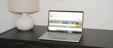 A laptop on a desk with a lamp beside it.