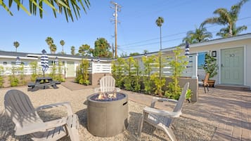 A patio area with Adirondack chairs, a fire pit, and a small building with a door labeled '10'.