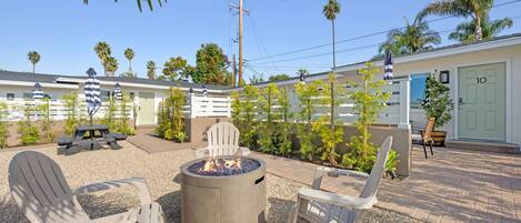 A patio area with Adirondack chairs, a fire pit, and a small building with a door labeled '10'.