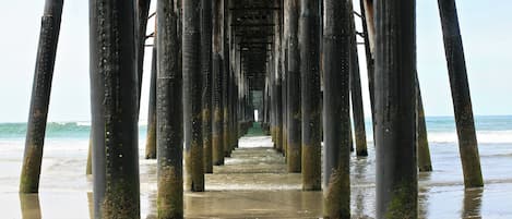 Une jetée qui s’avance dans l’eau et d’où l’on a une vue dégagée sur l’océan et la plage.