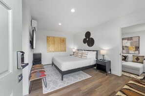 Une chambre à coucher moderne, avec un lit, des tables de chevet, un téléviseur et des œuvres d’art accrochées aux murs.