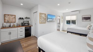 Ein modernes Schlafzimmer mit großem Bett, separatem Schlafbereich, einer Küchenzeile und Kunstwerken an den Wänden.