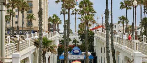 A coastal promenade with palm trees, a bridge, and a seafood restaurant.